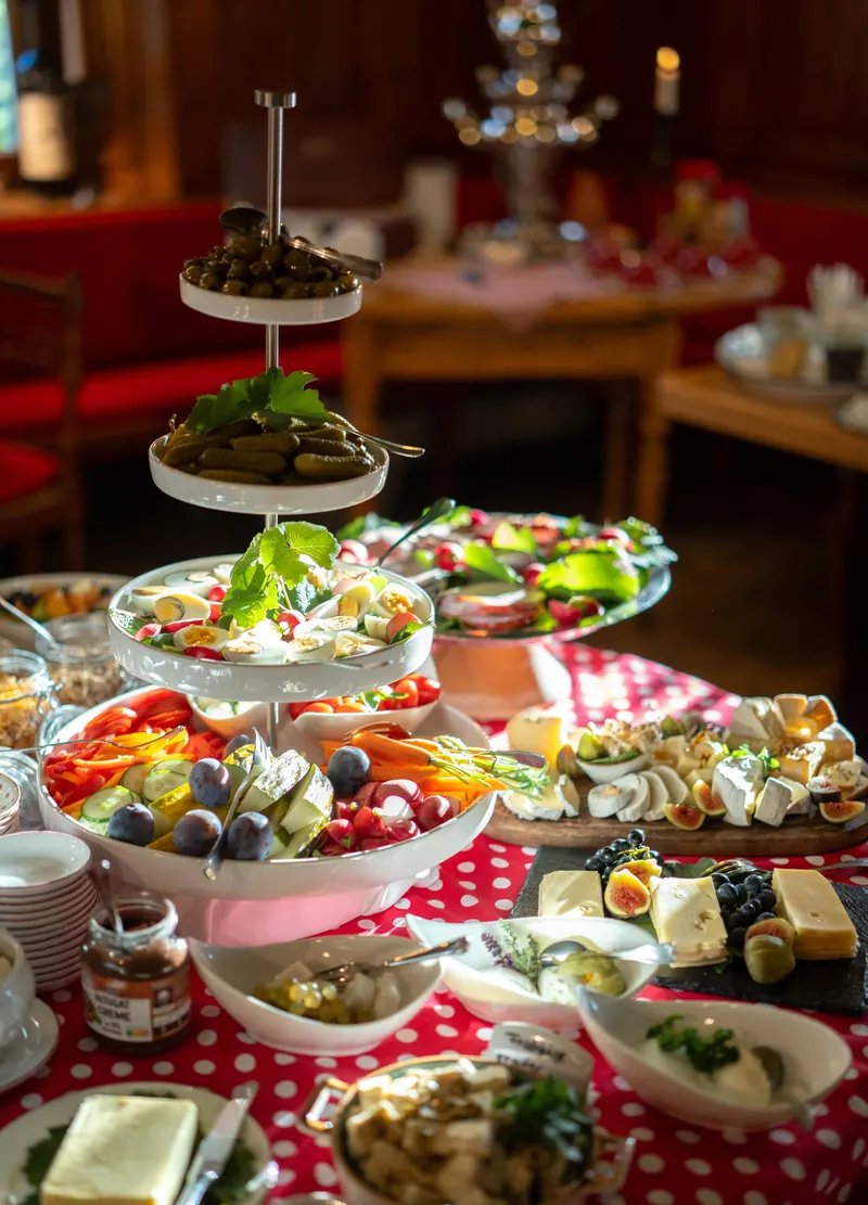 Frühstücksbuffet mit Etagere: Eier, Gemüse, Obst und Käse auf rot gepunkteter Tischdecke