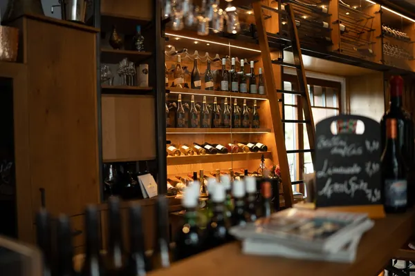 Weinregale bis unter die Decke, davor eine Kreidetafel auf der Theke